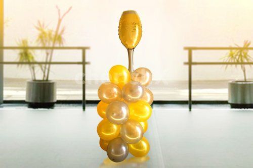 A Champagne Glass Foil Balloon placed on yellow bunches of balloons to add to the anniversary decor.