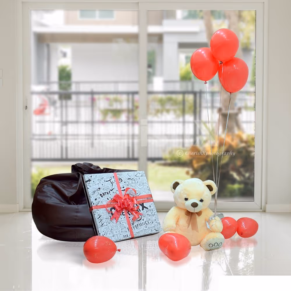 A Teddy Surplosion Box with a gift, teddy and balloons.