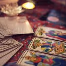 Close-up view of an Indian male tarot reader in a blue striped shirt explaining tarot cards to a couple in a cozy indoor setting.