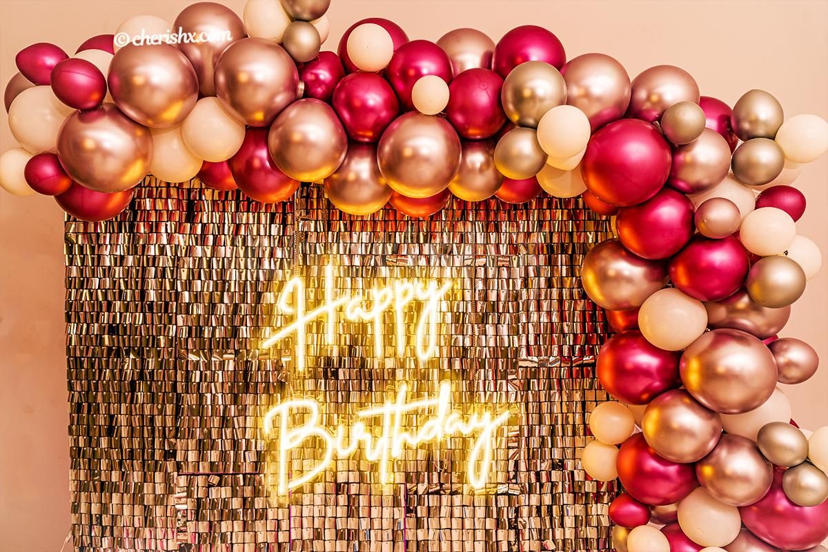 A wall covered with an arc of silver and pink chrome balloons.