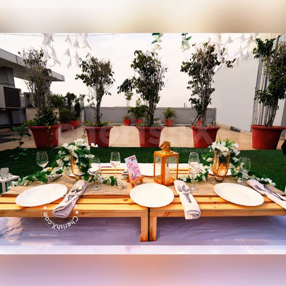 Low Dining Tables decorated with 2 Golden Vase filled with White Flower Bunches and 1 Golden Lamp placed on the table for the Boho Dining Experience.