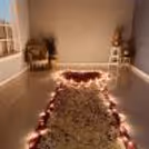 Romantic proposal setup with candles and fresh flower petals.