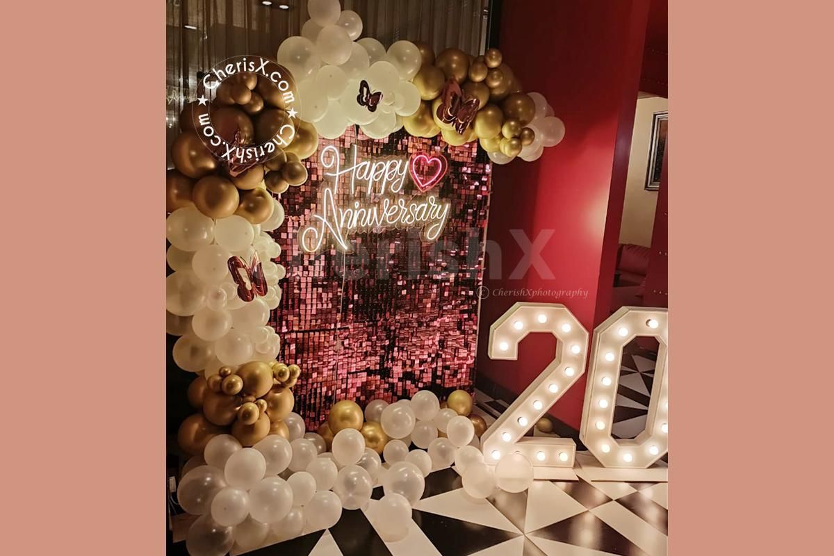 A wall covered with an arc of White & Golden Chrome balloons.