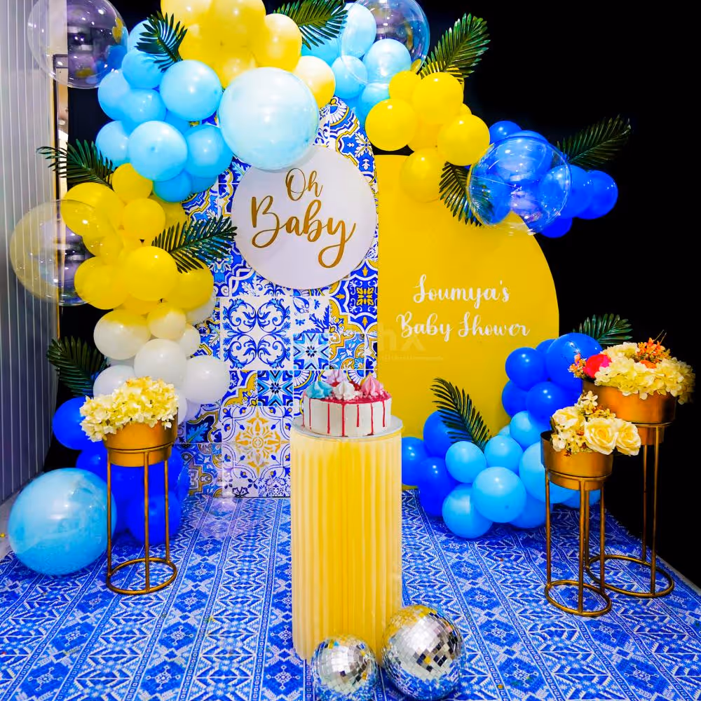 Picture-perfect moments await amidst a backdrop of sun board cutouts, a captivating 'Oh Baby' centrepiece, and a burst of yellow, white, and blue balloons.