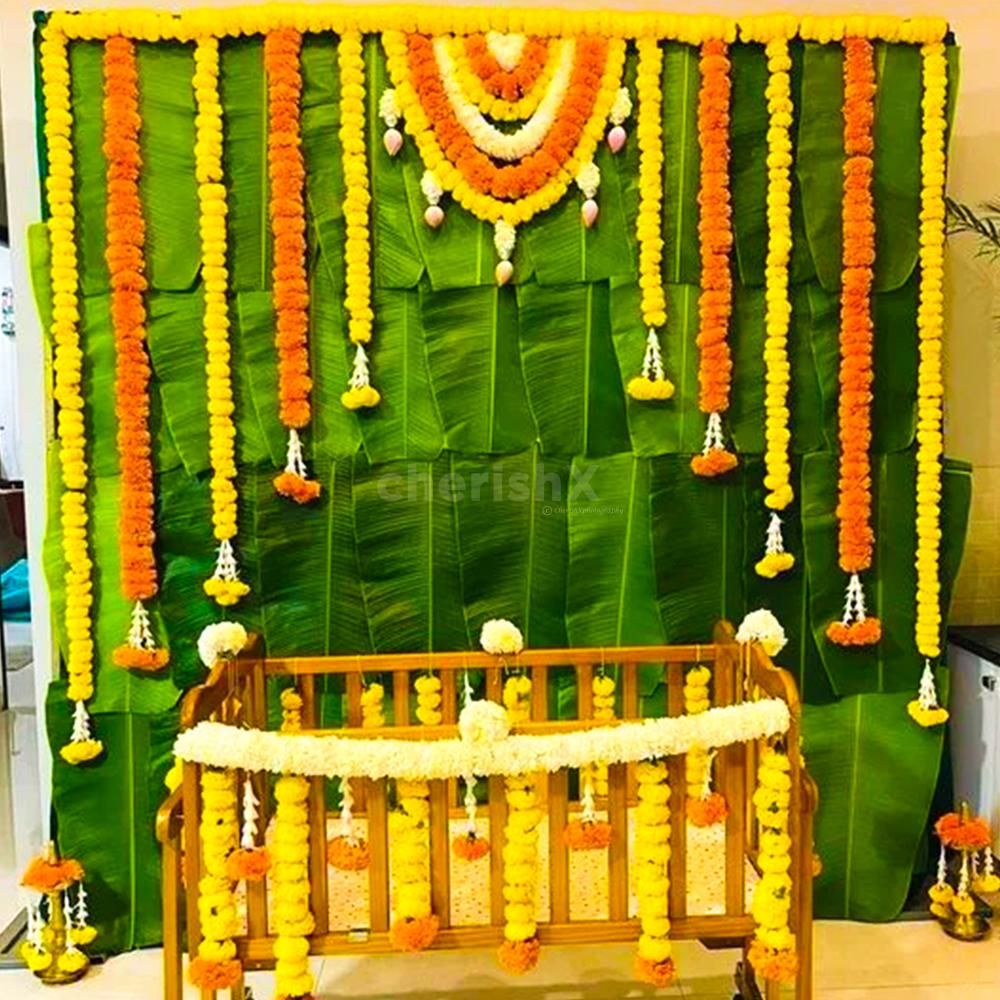 A mesmerizing backdrop adorned with vibrant banana leaves and orange marigold flowers creates a captivating ambience at the naming ceremony.