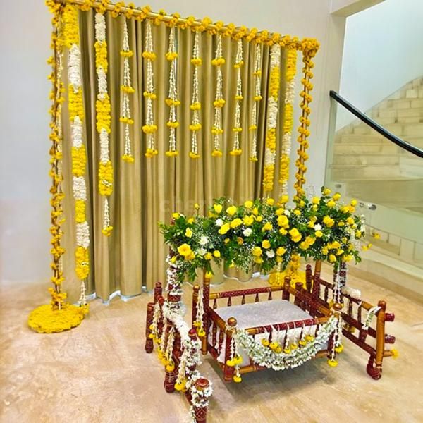 A gold-coloured backdrop adorned with 11 rows of marigold yellow and lily flowers, creates a captivating and visually striking centrepiece.