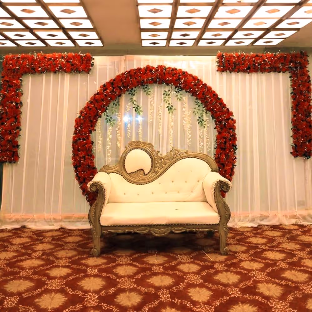 A stunning peach cloth backdrop adorned with natural red roses and leaves creates a captivating and romantic ambiance.
