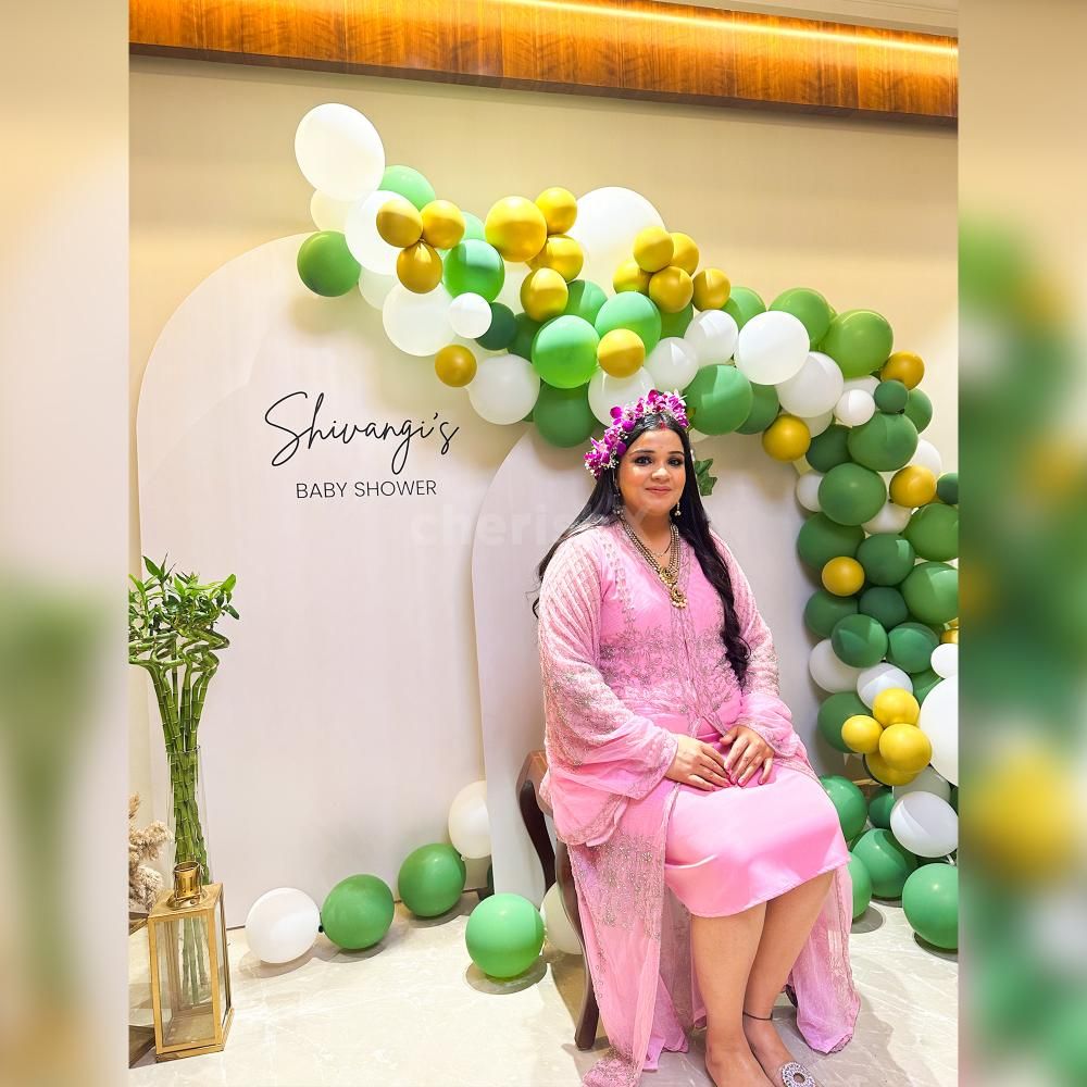 This baby shower decoration is about the balloon arch in shades of Bean Green Vintage, White Latex, and golden Chrome Balloons.