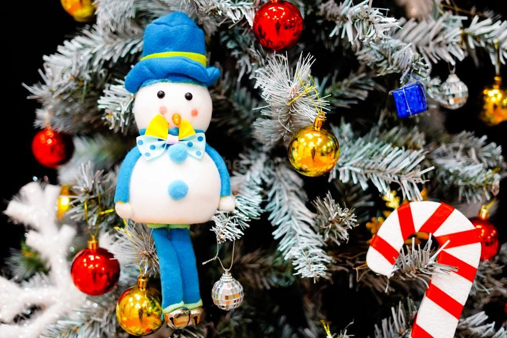 Golden snow cutouts, mirror balls, and a mix of festive decorations create a glittering display near the tree.