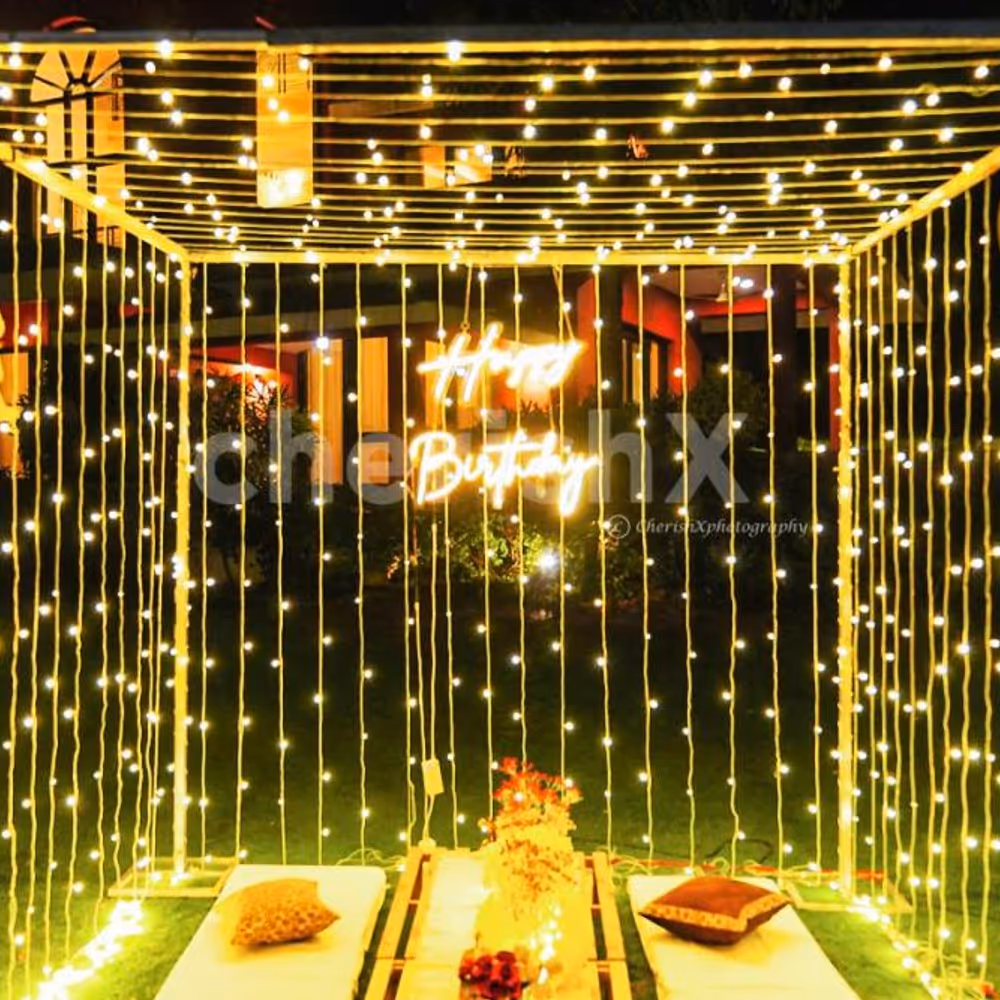 Wooden crates decorated with floor lamps, jute mats, and vases filled with artificial flowers, create a whimsical atmosphere in the cabana.