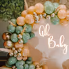 An arch of balloons in retro peach, vintage olive green, and golden chrome hues.