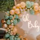 An arch of balloons in retro peach, vintage olive green, and golden chrome hues.