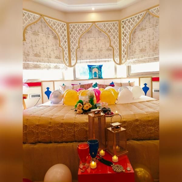 Elegantly adorned room with Mughal artwork and balloon decorations creating a joyous atmosphere.