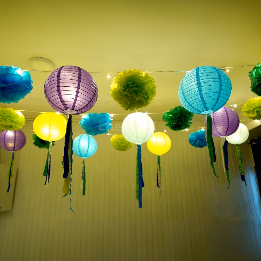 A collection of light green, dark green, and light blue pom poms, part of festive decorations.