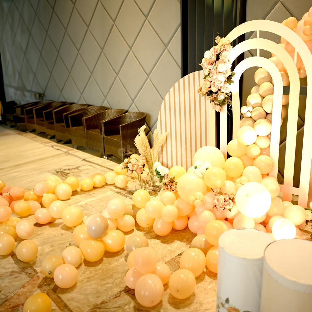 Large macron peach balloons, flower bunches, glass vases, decorative cages, and disco lights create a whimsical atmosphere.