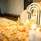 Large macron peach balloons, flower bunches, glass vases, decorative cages, and disco lights create a whimsical atmosphere.