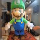 Mario cartoon character in green costume doing actions for interactive entertainment at a child's birthday party.