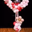 A balloon arch on the heart stand is decorated with butterfly cutouts, ribbon rows, and more.