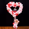 A bubble balloon with red feathers and a couple of pictures makes the bouquet customized.