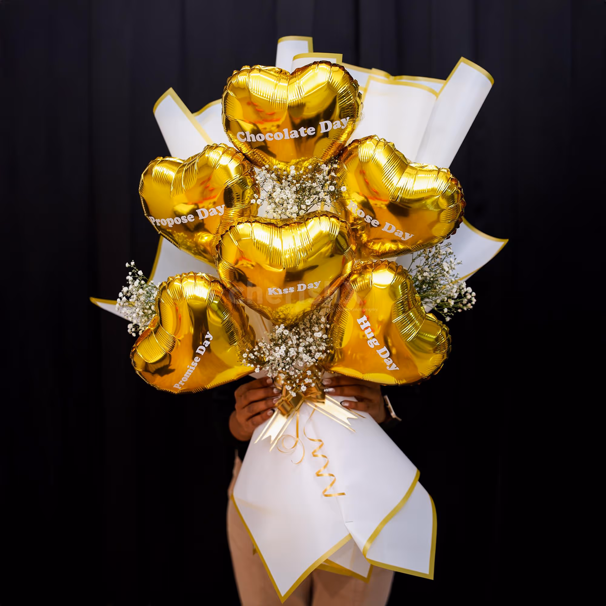 Baby breath bunches highlight contrast against golden heart-shaped balloons.