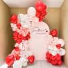 Colorful pastel pink, white, red, and metallic tones create a beautiful balloon arch.