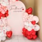 Large and small red heart foil balloons provide emotion in the baby welcome arrangement.