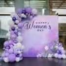 A grand-sized vibrant flex banner on a stand glows with "Happy Women's Day" Signage