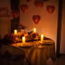 A beautifully decorated private dining table with rose petals, candles and wine for the perfect romantic evening.