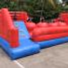 8 to 12 kids playing on inflatable obstacle course with slides and climbing for fun birthday celebration