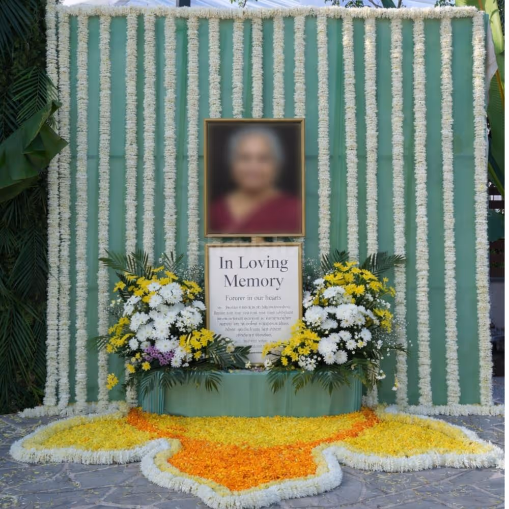 Fresh Flower Backdrop With Green Draping And Floral Rangoli On The Floor For A Peaceful Remembrance Setup