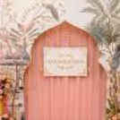 Annaprashan Sunboard On A Pink Draped Wall With Peacock Theme Artwork.