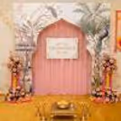 Annaprashan Decor With A Pink Crepe Fabric In The Backdrop. Also, It Has Bell Hangings, Lights, And Function Items.