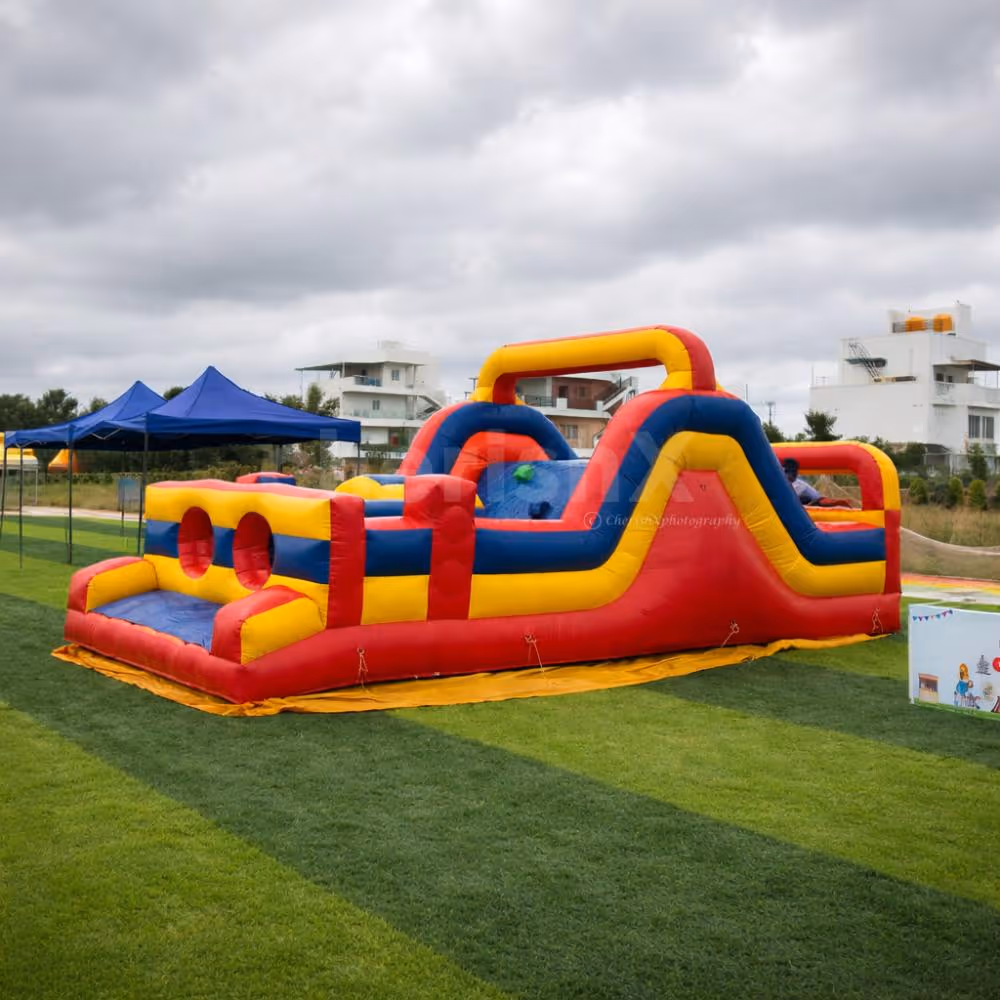 Colorful inflatable challenge arena with climbing and sliding sections for a kids' party activity.