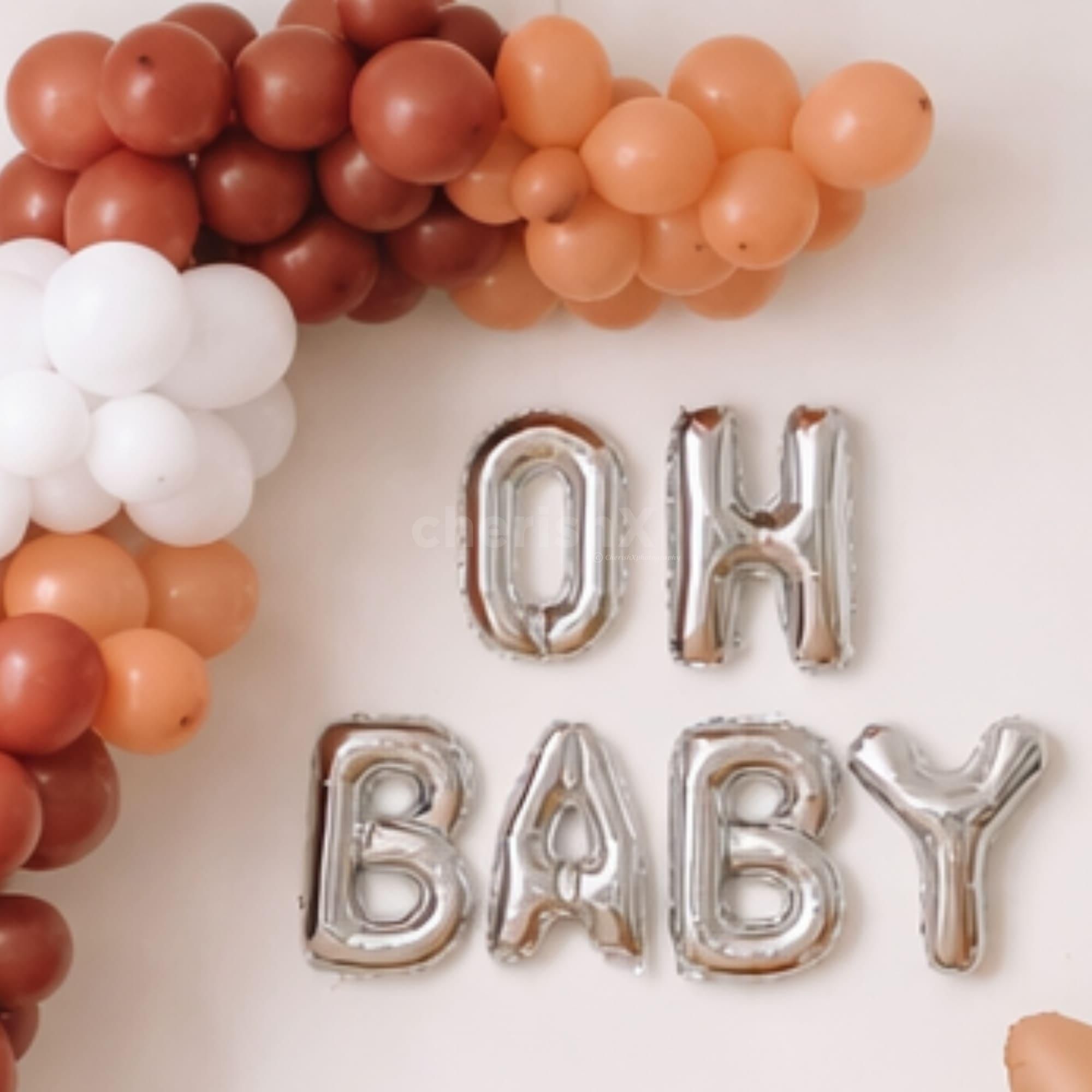 A balloon arch with a teddy, a moon balloon, and OH BABY foil letters forms a beautiful 
Baby shower setup.