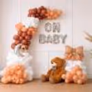Mom-To-Be Standing Beside Baby Shower Balloon Decor With A Soft Theme