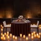 Romantic table for two near a fountain, elegant decor, candles, beautifully lit proposal background.