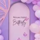 The decor features graceful butterfly cutouts and a delightful blend of purple and pink balloons.