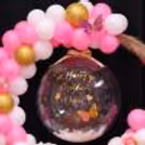Multiple Balloons, Artificial Flowers, A Message Card And A Golden Ribbon Bow Steal The Show