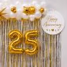 Beautiful 25th Anniversary decor featuring Gold Balloons, White Balloons, White satin backdrop, etc.