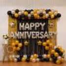 Black, silver and gold anniversary setup with balloons and shimmering frill curtains.