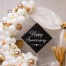 Anniversary balloon arch in white and champagne color with floral design, satin draped.