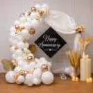 Flowers and white balloons for champagne anniversary decoration and its Happy Anniversary sign.