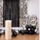 The photo backdrop is silver number foil balloons and a white pedestal for Anniversary decor.