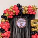 Red and black balloon garland with gold star foil balloons for a birthday.