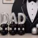 In the centre of a round Father's Day display with black and silver chrome balloon clusters arranged around it.