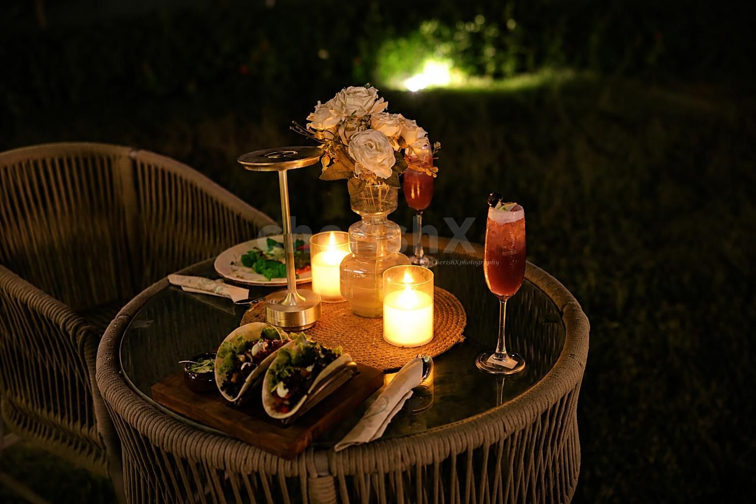 A dreamy outdoor candlelight dinner by CherishX, designed with glowing candles, elegant flowers, cozy seating, and a magical horse stable backdrop