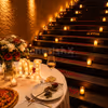 CherishX candlelight dinner setup with a romantic stairway, rose petals, premium table décor, and cozy lighting for couples.