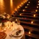 CherishX candlelight dinner setup with a romantic stairway, rose petals, premium table décor, and cozy lighting for couples.