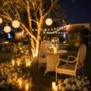 A luxurious outdoor proposal setting featuring white flowers, warm candlelight, and refined decor with a serene farm backdrop.