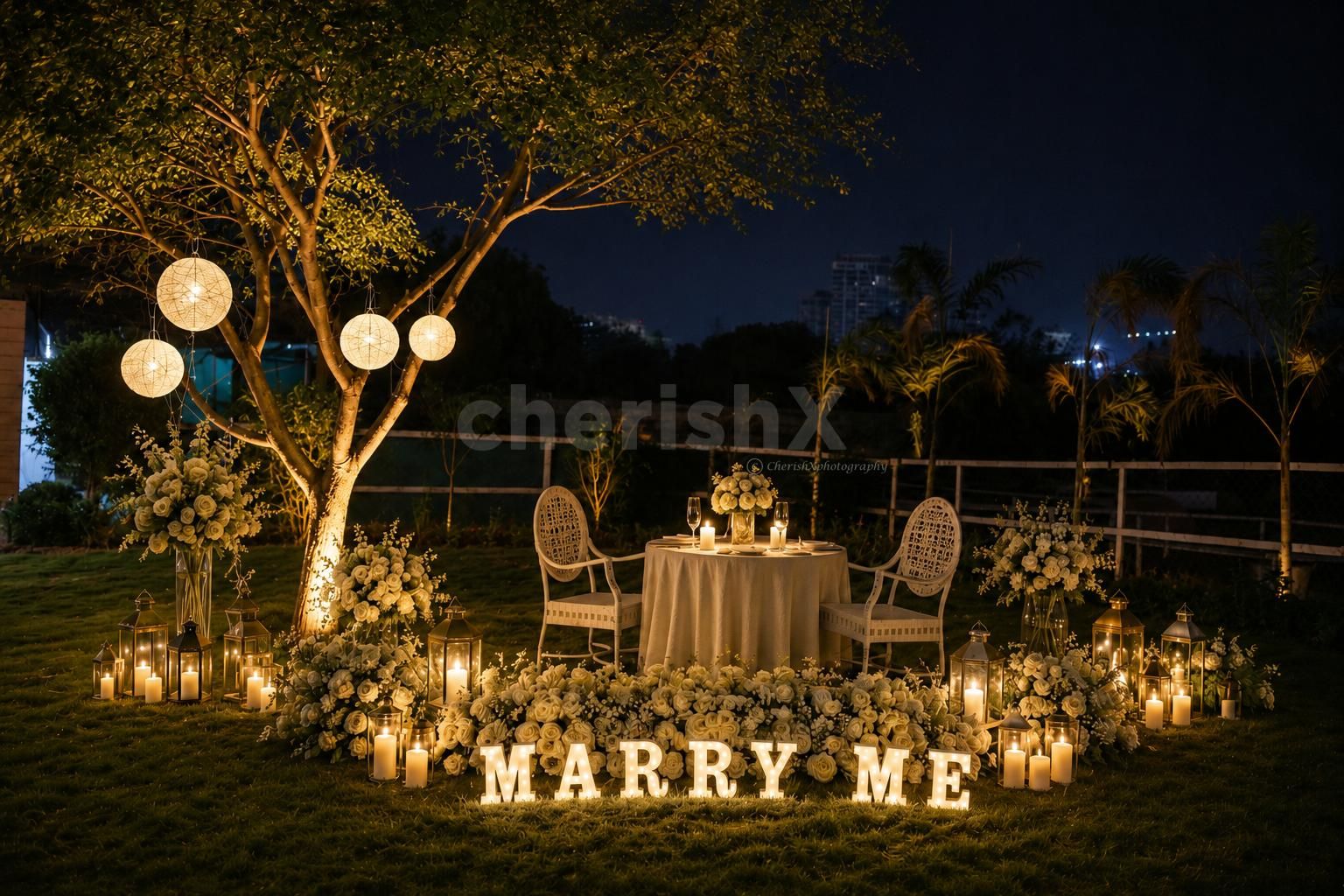 candlelight proposal setup with white floral arrangements on a lush lawn, creating a timeless romantic ambiance.